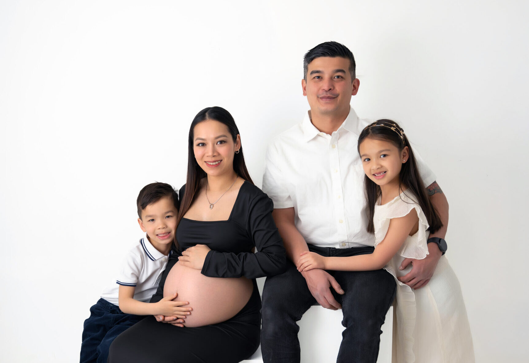 A monocromatic portrait of a family huddled together smiling.
