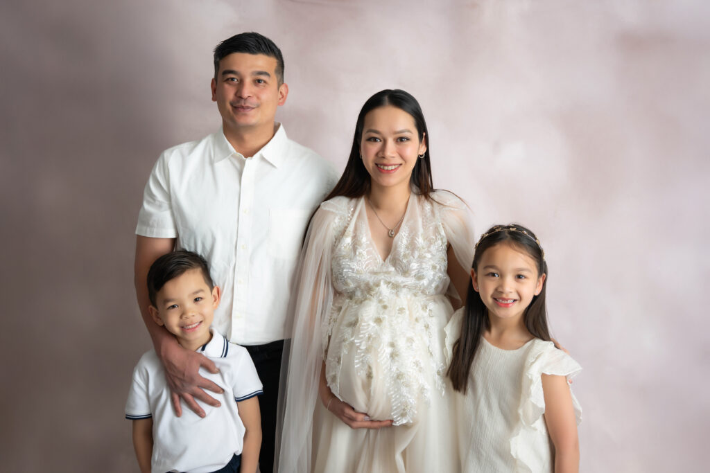 Family of four standing together with smiles on their faces
